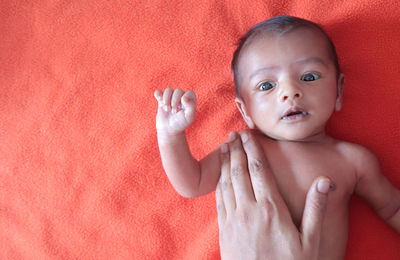 Cropped hands of woman massaging shirtless baby boy on bed at home