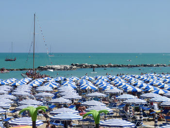 Blue umbrellas at beach against clear sky