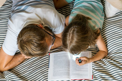 Father and son playing and reading in a kid tent at home.