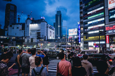 People on street against illuminated buildings in city at night