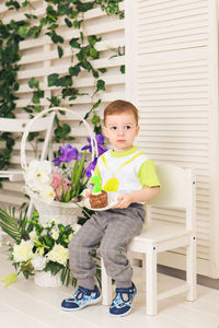 Portrait of cute boy sitting on potted plant