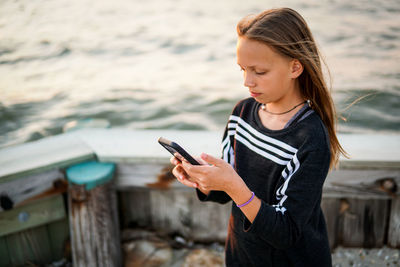 Teenage girl looking at camera while standing on mobile phone