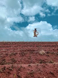 Low angle view of person jumping on field against sky
