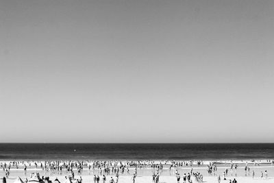 People at beach against clear sky