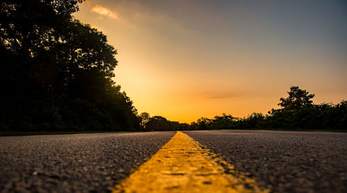 Surface level of road against sky during sunset