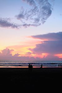 Silhouette people on beach against sky during sunset