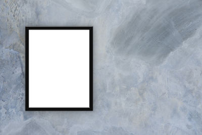 Close-up of blank picture frame on concrete wall