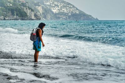 Rear view of man walking on beach against clear sky