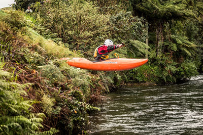 Man surfing on river against trees