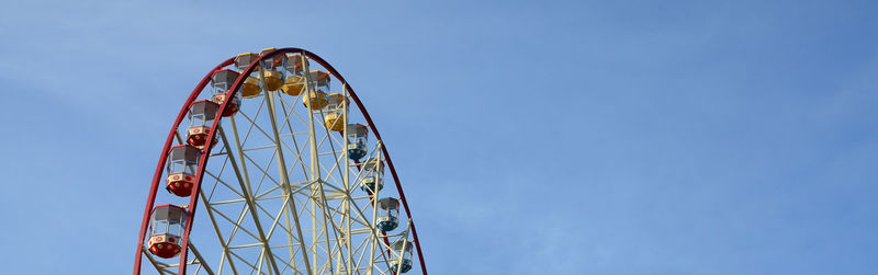 Low angle view of ferris wheel against clear blue sky