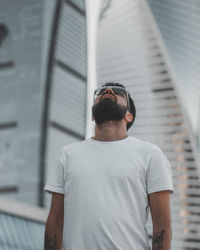 Young man wearing sunglasses standing against wall