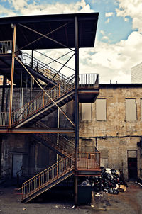 Metal staircase by old building against sky