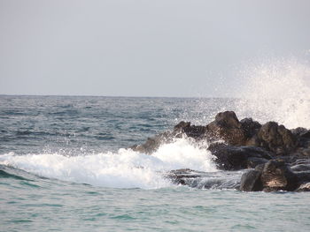 Waves splashing on sea against sky