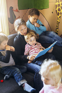 High angle view of teacher telling story to children in kindergarten