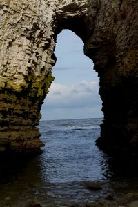 Rock formation in sea against sky