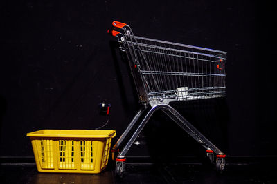 Yellow plastic basket by shopping cart in darkroom