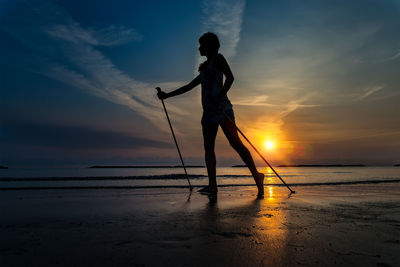 Silhouette man standing on beach against sky during sunset