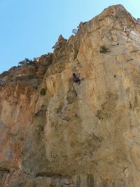 Low angle view of person on cliff against clear sky