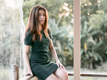 Portrait of young woman sitting on railing