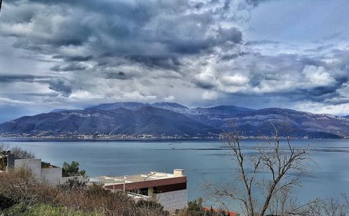 Scenic view of sea by city against dramatic sky