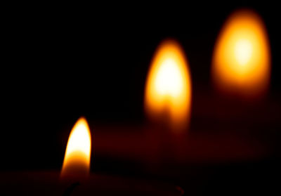 Close-up of lit candles in darkroom