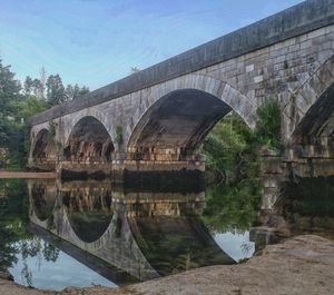 Arch bridge over river against sky