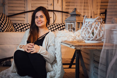 Portrait of smiling young woman sitting on table