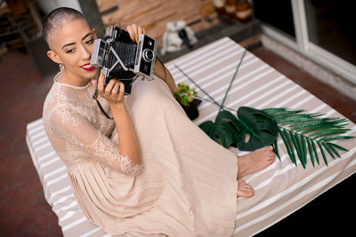 Portrait of young woman holding instant film camera