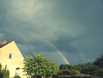 Low angle view of rainbow over house against sky