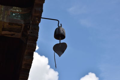 Low angle view of electric lamp hanging against blue sky