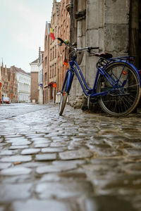 Bicycles on street by canal against buildings in city