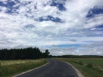 Road amidst field against sky