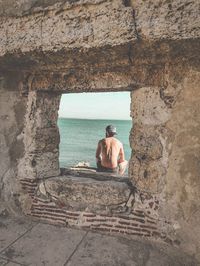 Man sitting on rock by sea