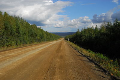 Road passing through landscape against cloudy sky