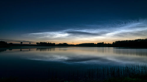 Beautiful night landscape with white silver clouds over the lake, blurred foreground