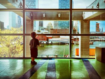 Full length rear view of boy looking through glass window at boston children museum