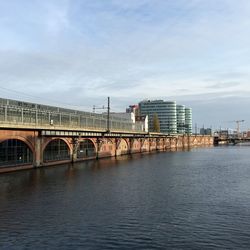 Bridge over river in city against sky