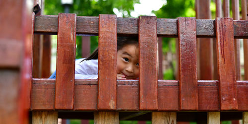 Low angle portrait of girl on wooden play equipment at park