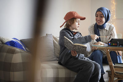 Mother wearing hijab helping son doing homework