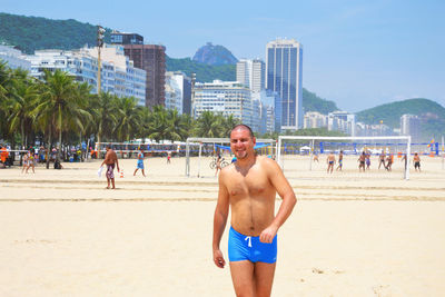 Happy shirtless man walking at beach