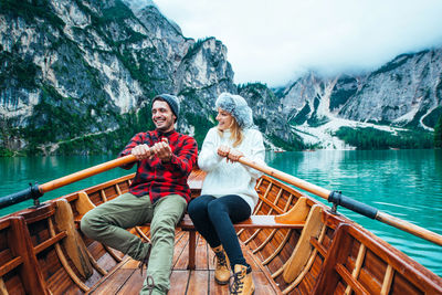 Woman sitting by lake against mountain