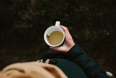 High angle view of hand holding cup of tea.