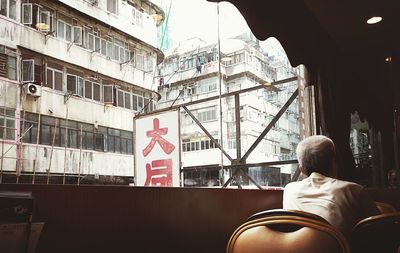 Rear view of man sitting on seat in city