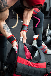 Crop strong sportsman disinfecting weight vest in gym before workout during coronavirus epidemic