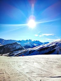 Scenic view of snowcapped mountains against blue sky on sunny day