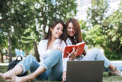 Young asian girls students working on laptop in city park