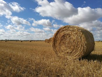 Hay bales on field against sky