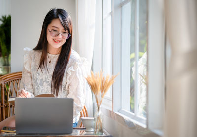 Young woman using phone on table
