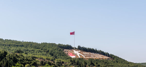 Red flag on built structure against clear sky