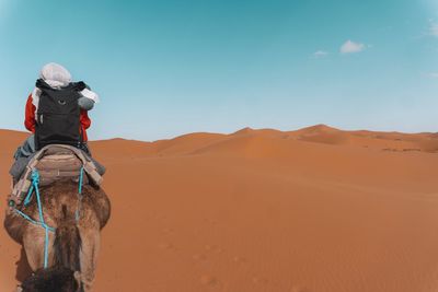 View of man riding horse on desert